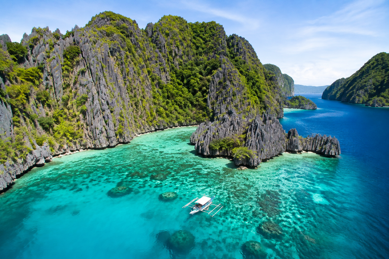 Illustrative Palawan limestone cliffs and turquoise lagoon with an outrigger boat