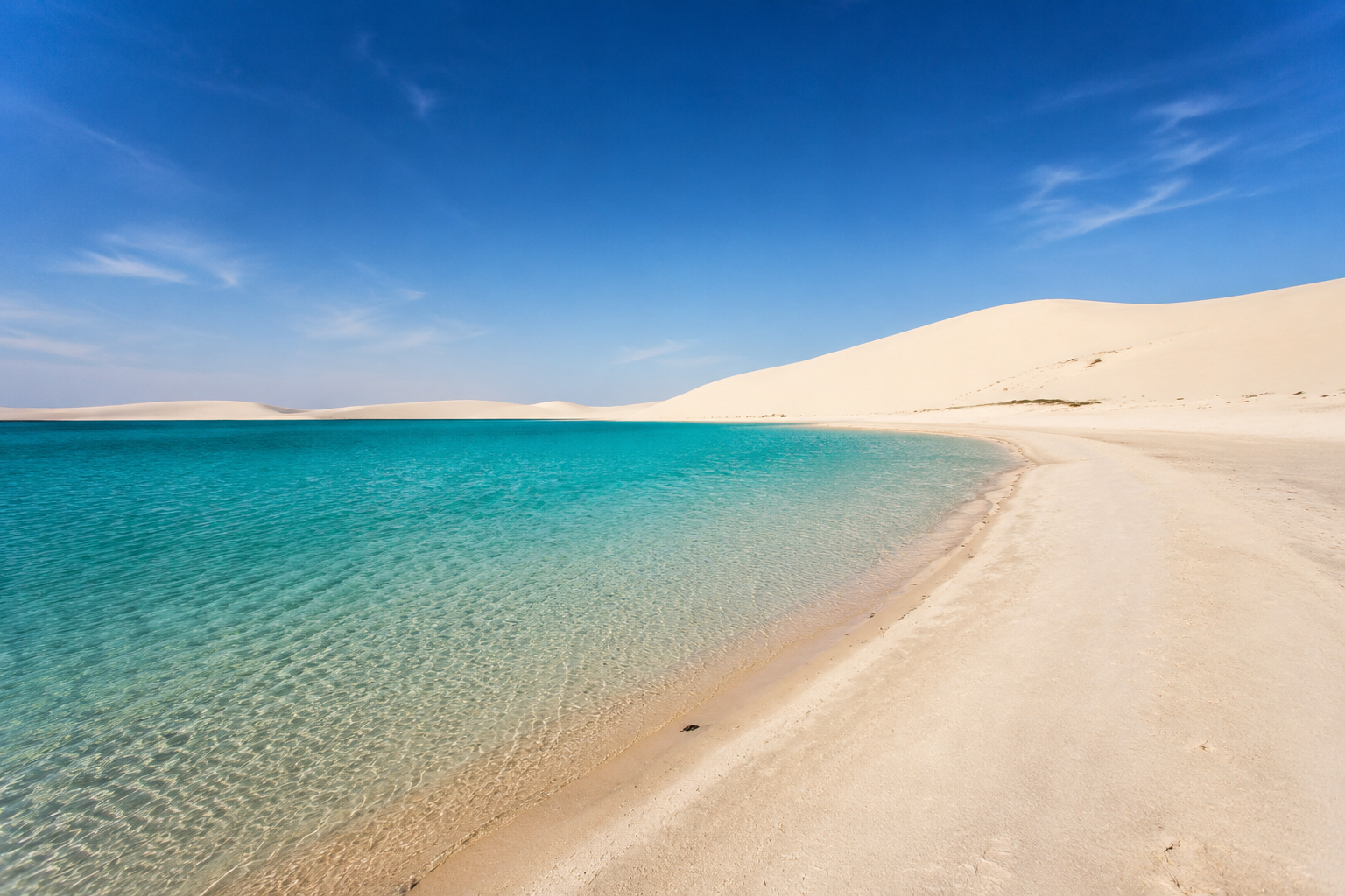 Pale desert dunes beside the turquoise Inland Sea in Qatar